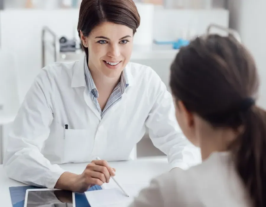 Adult-Gerontology Nurse Practitioner (AGNP) discussing treatment plan with patient and smiling